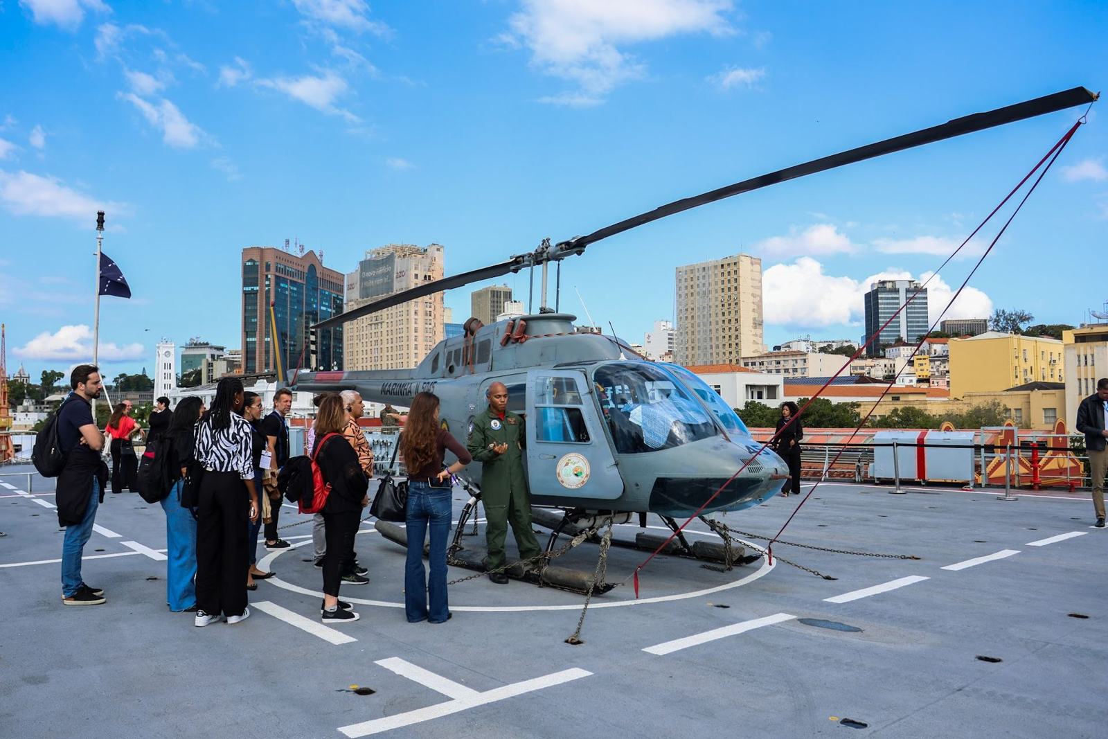 Visitantes ao redor de um helicóptero no convés de voo